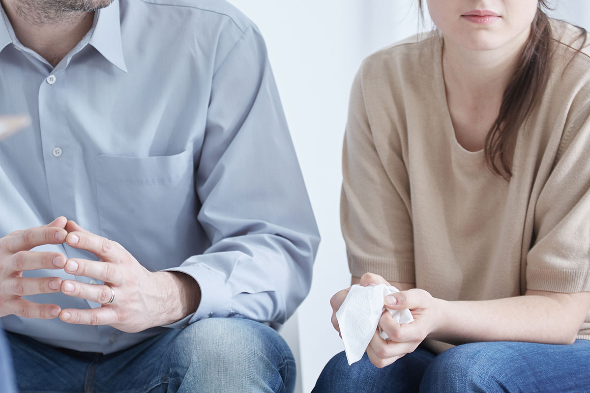 a woman holds a tissue during a meeting about divorce