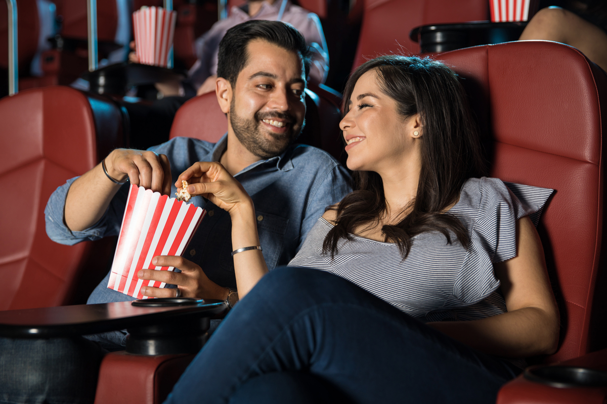 Married couple sitting at a movie theater eating popcorn