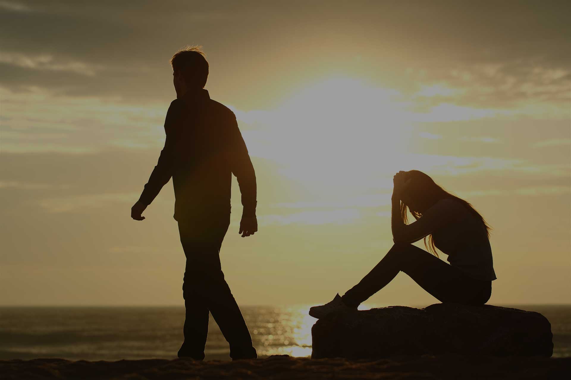 married couple argues on the beach as the man walks away