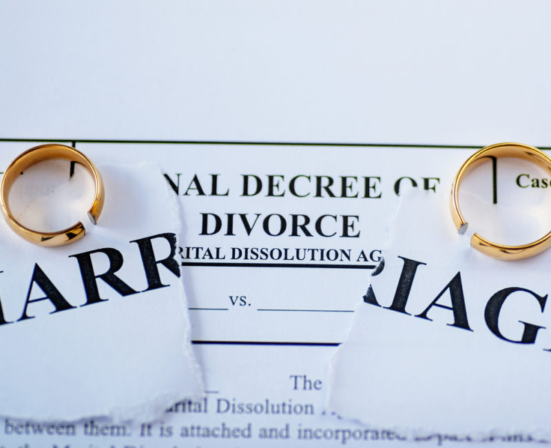 Two wedding rings on top of divorce papers